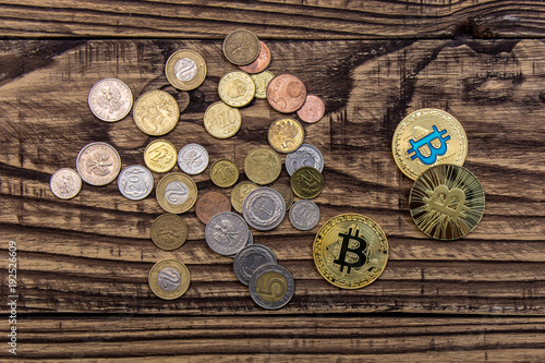 bitcoins and simple coins lie on wooden table