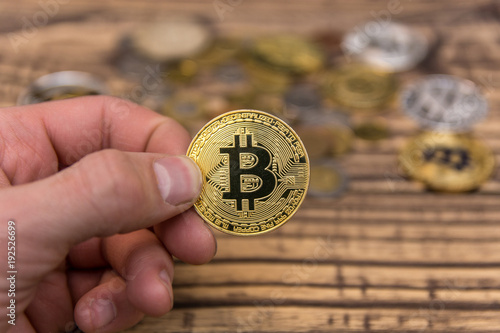  bitcoin holding in man’s fingers on old wooden background