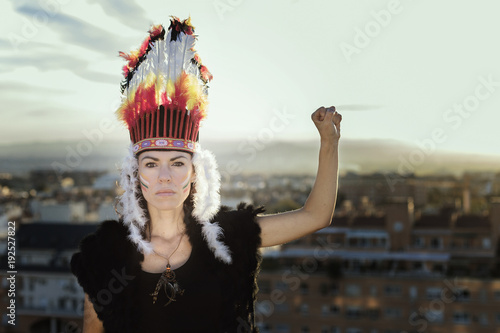Portrait of a woman wearing a feather headdress holding her fist in the air, Granada, Andalucia, Spain