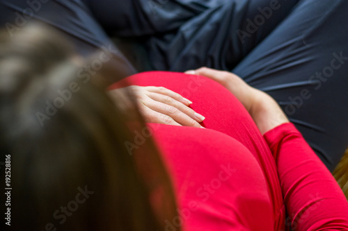 Closeup of mother holding her pregnant belly.