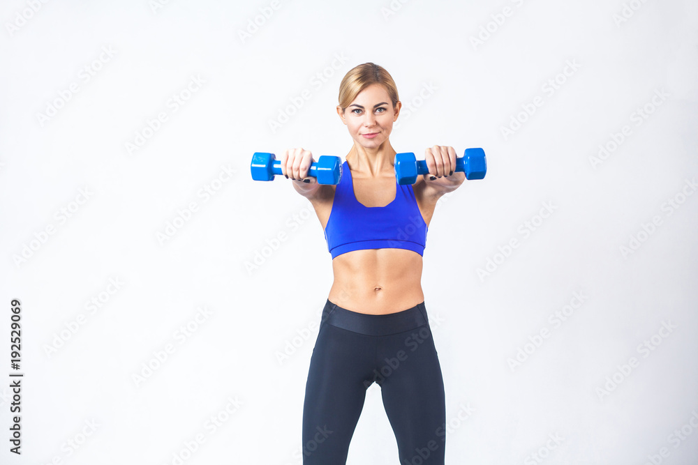 Portrait of blonde woman, demonstrate two blue dumbbells at camera Portrait of blonde woman, demonstrate two blue dumbbells at camera