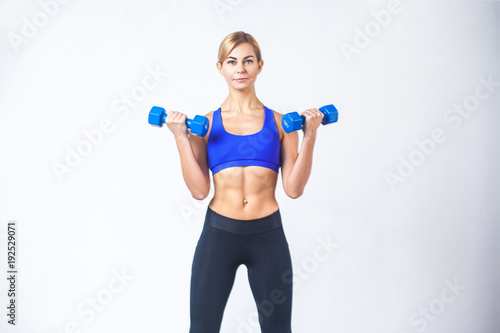 Portrait of woman with perfect body, holding two blue dumbbells