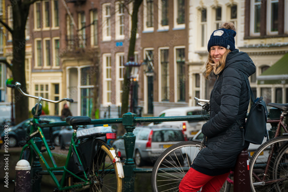 Tourist in Amsterdam - woman in her 30s waiting beside bicycles on a bridge in Amsterdam