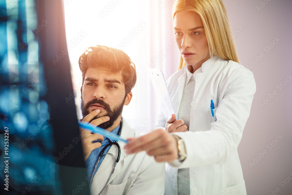Two serious doctors reviewing patient medical results. Doctors looking at x-ray. Two serious doctors reviewing patient medical results. Doctors looking at x-ray.