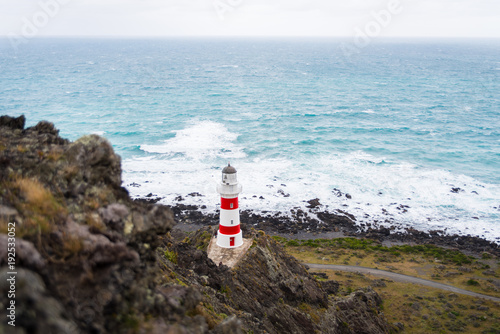 A light house with the oceand in the background at Cape Palliser, New Zealand.  photo