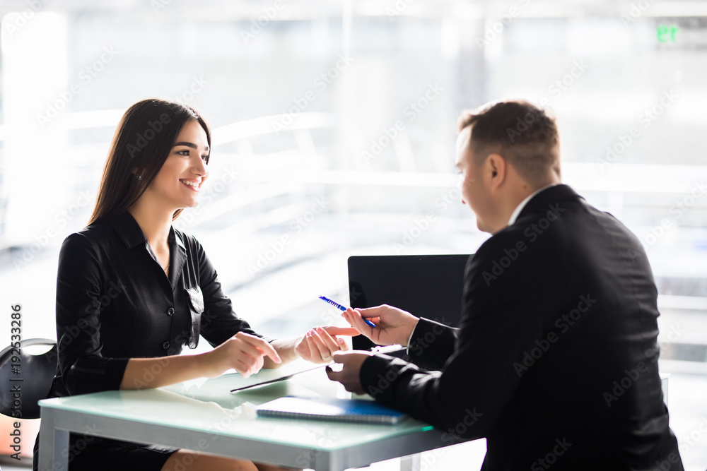 Businesspeople sitting at a table and signing a contract at office Businesspeople sitting at a table and signing a contract at office