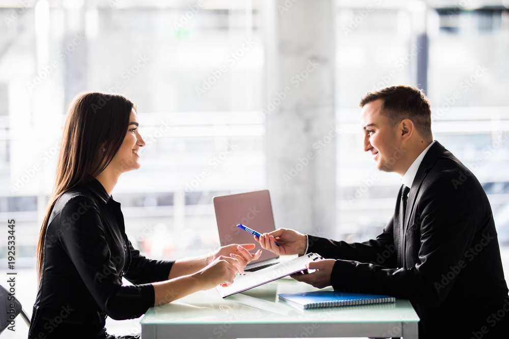 Businesspeople sitting at a table and signing a contract at office Businesspeople sitting at a table and signing a contract at office