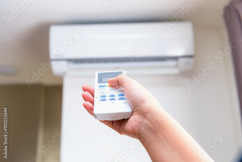 Quadro su tela Close up view of hand operating air conditioner remote control