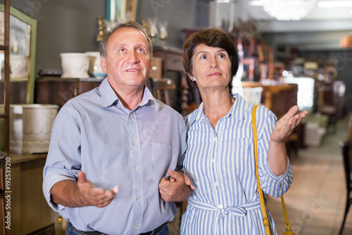 Man with wife are choosing antique furniture