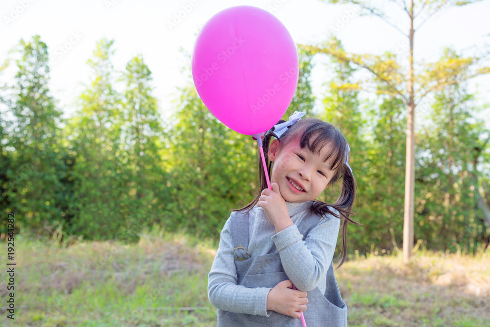 Little asian girl holding balloons and smiles in park Little asian girl holding balloons and smiles in park