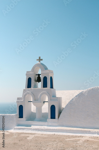 White church bell tower with blue sky in Oia, Santorini, Greece