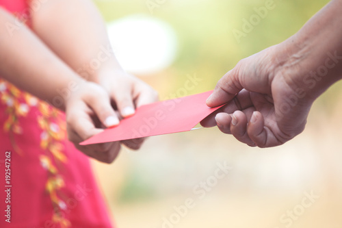 Parent give money in red envelope to little child girl for celebrate in Chinese New Year