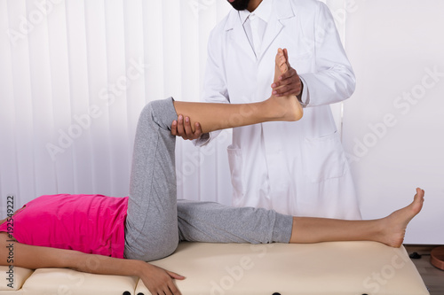 Physiotherapist Giving Leg Exercise To Patient