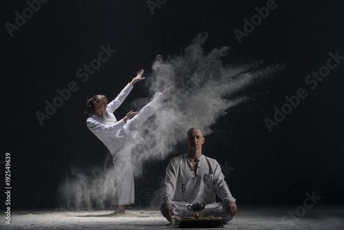 Two male doing yoga in a white dust cloud view