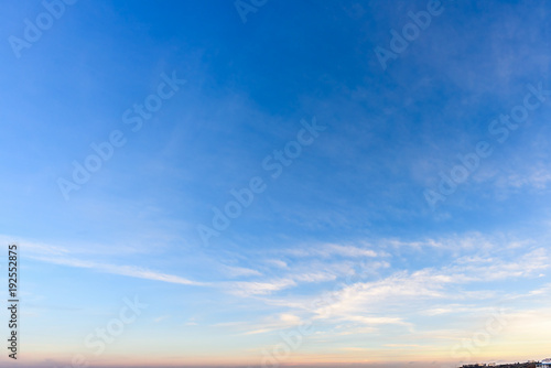 A huge  endless sky  illuminated by the rising sun  pink  blue  white fluffy clouds and a forest