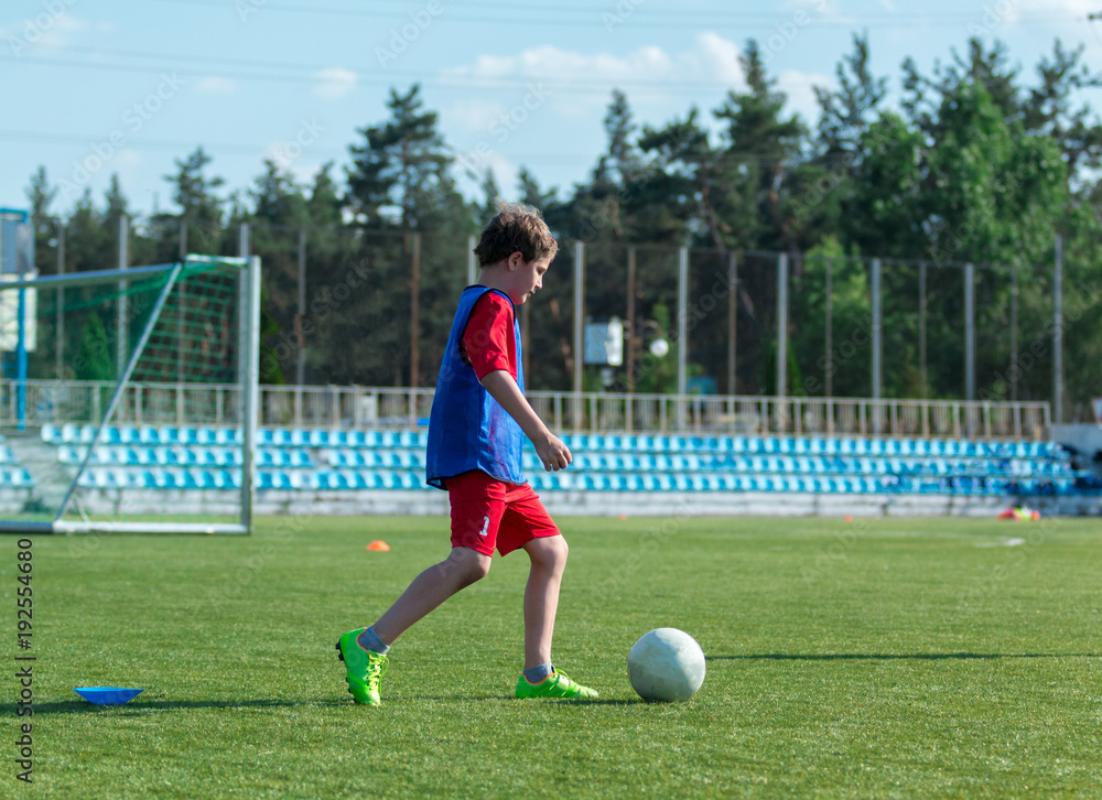 boy trains dribbling on the summer stadium during the training boy trains dribbling on the summer stadium during the training