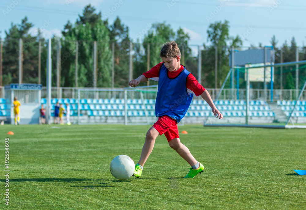 boy trains dribbling on the summer stadium during the training