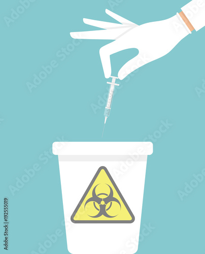 Hand throwing away used hypodermic needle into a trash bin with biohazard sign on it