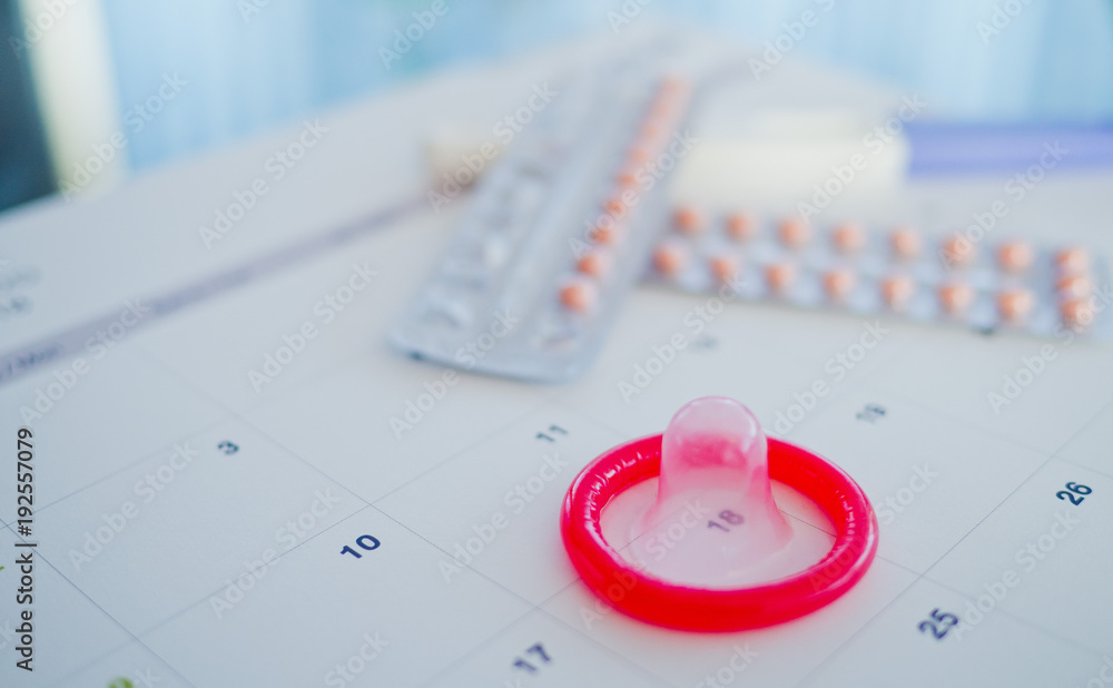 Fototapeta premium condom with contraceptive and pregnancy test on calendar, Birth control pill, safe sex, healthcare concept