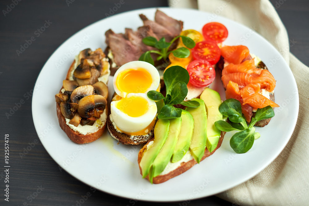 Bruschetta, assorted, different fillings, on plates with a soft-boiled egg in the middle