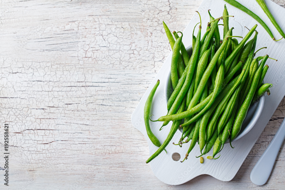 Green beans in white bowl on cutting board. Top view. Copy space Green beans in white bowl on cutting board. Top view. Copy space