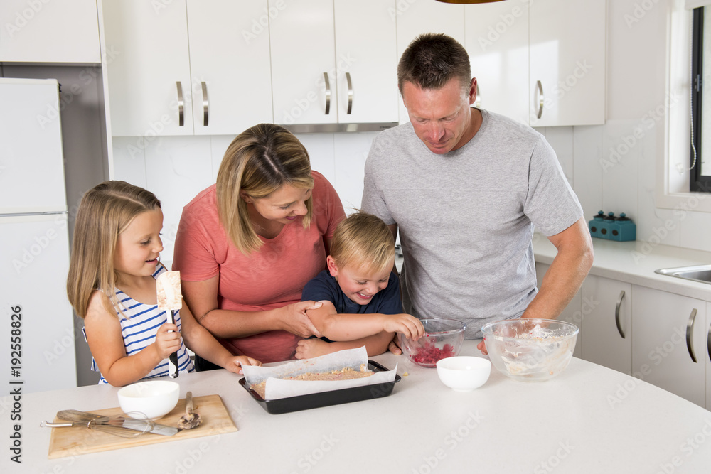 young happy couple baking together with little son and young beautiful daughter at home kitchen having fun playing with cream young happy couple baking together with little son and young beautiful daughter at home kitchen having fun playing with cream