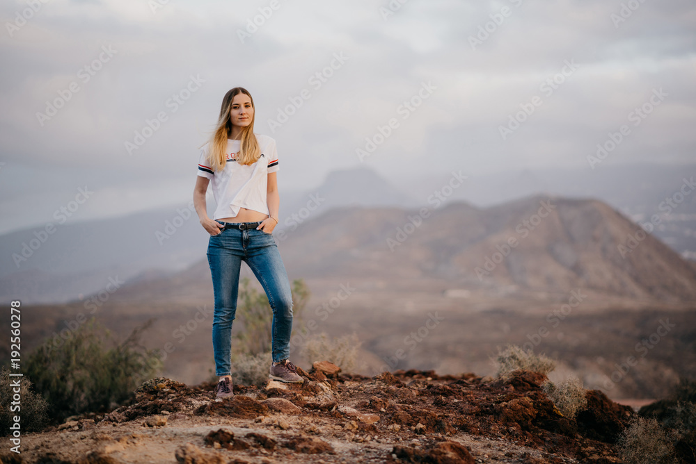 Beautiful girl watches straight and poses in the mountains on the sunrise. Tenerife Beautiful girl watches straight and poses in the mountains on the sunrise. Tenerife