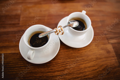 wedding bouquet and coffee with the wedding rings on the table photo