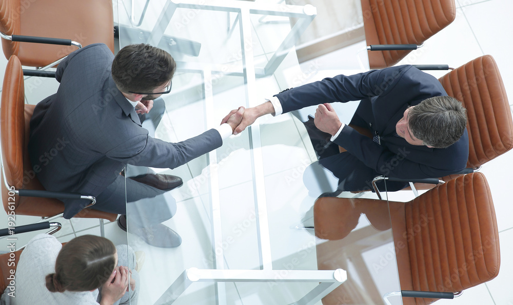 © ASDF - Handshake across the table. Meeting around a boardroom table. © ASDF - Handshake across the table. Meeting around a boardroom table.