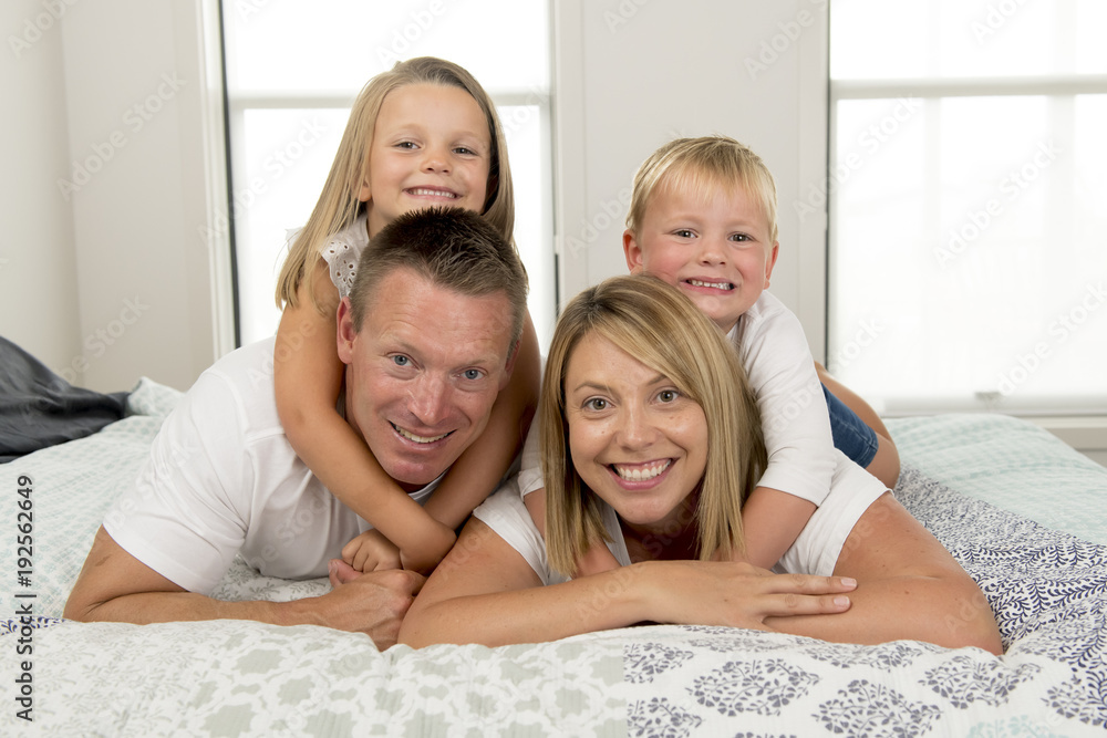 young beautiful and radiant couple 30 to 40 years old smiling happy posing sweet lying on bed with little son and beautiful daughter at home young beautiful and radiant couple 30 to 40 years old smiling happy posing sweet lying on bed with little son and beautiful daughter at home