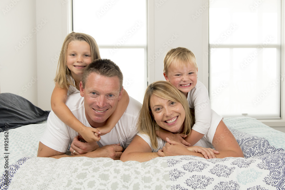 young beautiful and radiant couple 30 to 40 years old smiling happy posing sweet lying on bed with little son and beautiful daughter at home young beautiful and radiant couple 30 to 40 years old smiling happy posing sweet lying on bed with little son and beautiful daughter at home