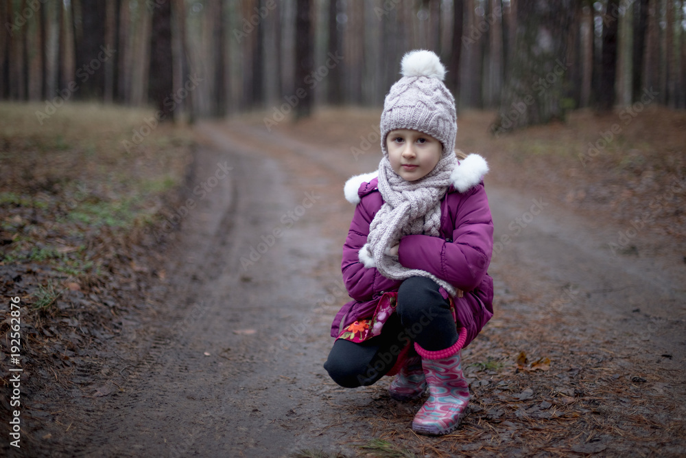 Little cute girl posing on the road in the pine forest in autumn time Little cute girl posing on the road in the pine forest in autumn time