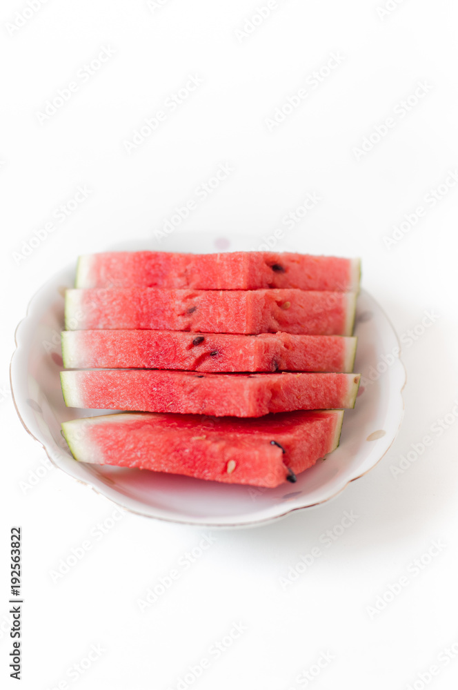 Five slices of juicy, freshly cut watermelon with black seed on white plate on white background Five slices of juicy, freshly cut watermelon with black seed on white plate on white background