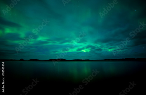 Northern lights dancing over calm lake. Farnebofjarden national park in Sweden © Conny Sjostrom
