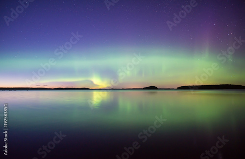 Northern lights dancing over calm lake. Farnebofjarden national park in Sweden