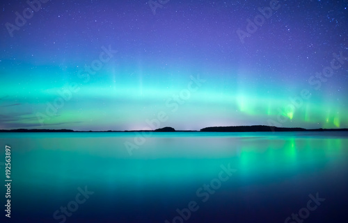 Northern lights dancing over calm lake. Farnebofjarden national park in Sweden photo