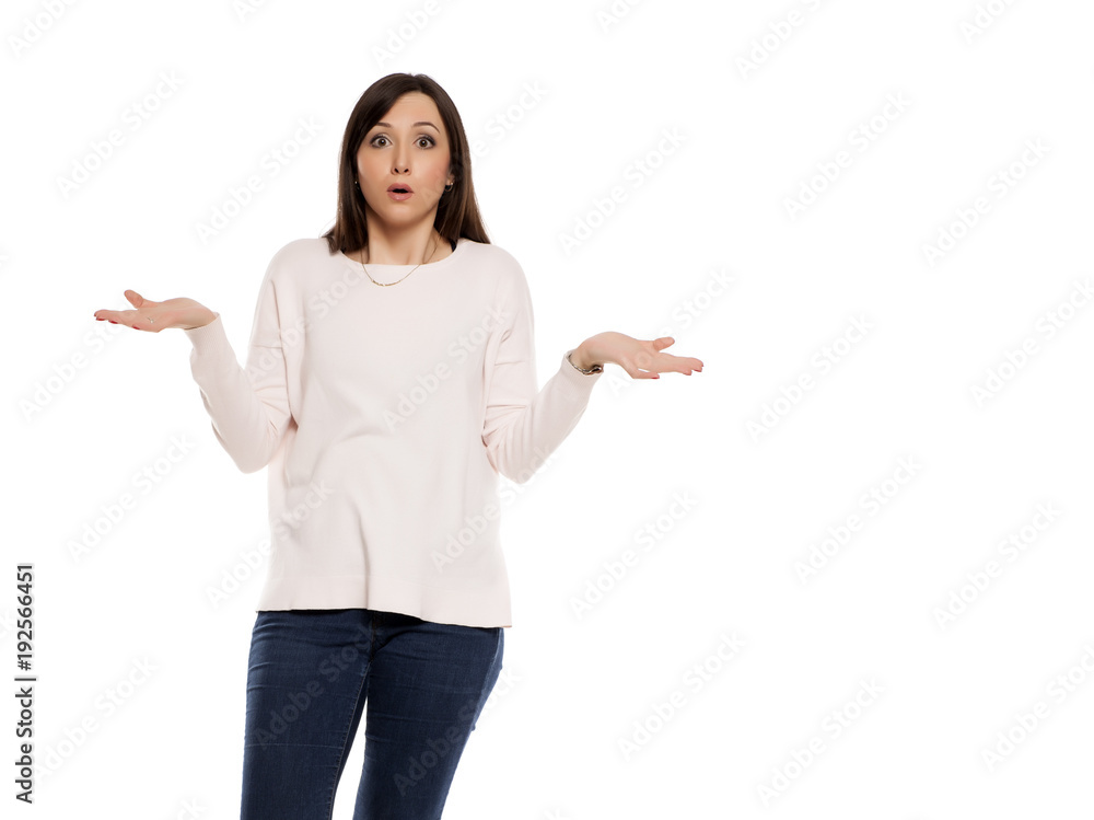 Young woman in jeans, blouse and snekaers with questionable gesture on white backgeound Young woman in jeans, blouse and snekaers with questionable gesture on white backgeound