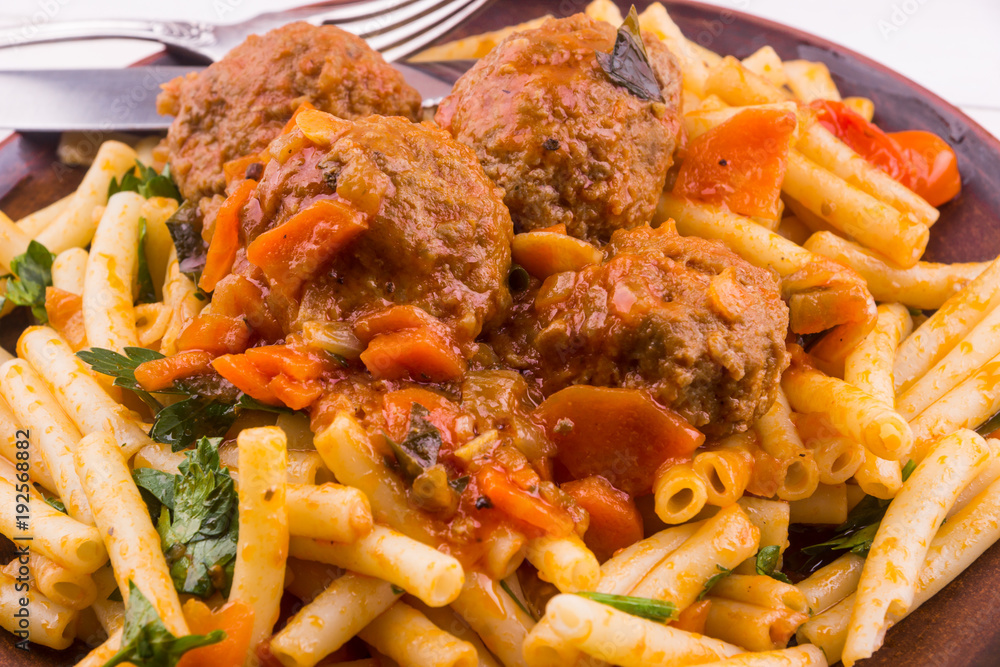 Macaroni with meatballs in tomato sauce with vegetables close-up Macaroni with meatballs in tomato sauce with vegetables close-up