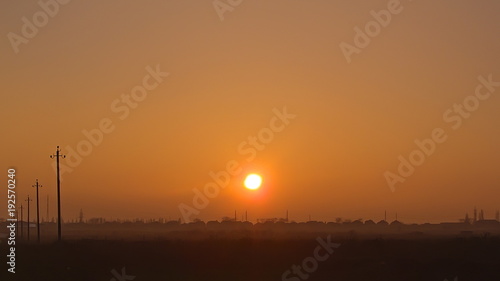 the setting sun over the roofs of houses. a haze over the field. natural background.