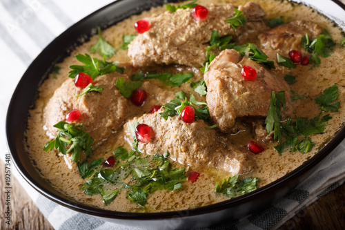 Georgian spicy satsivi with chicken and pomegranate close-up in a bowl on the table. horizontal photo