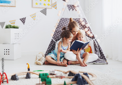 family mother reading to children book in tent at home