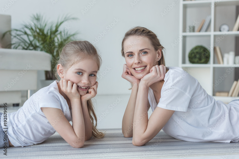 happy mother and daughter lying on floor together and looking at camera happy mother and daughter lying on floor together and looking at camera