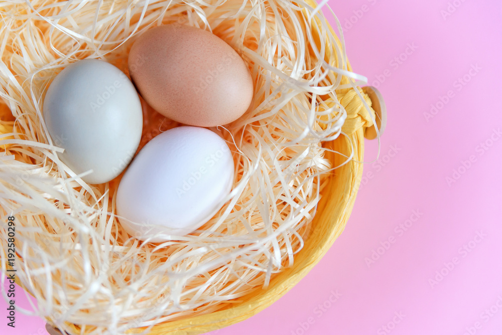 Easter eggs of different colors in a wicker basket on a pink background, Top view, Flat lay. Easter concept. Easter eggs of different colors in a wicker basket on a pink background, Top view, Flat lay. Easter concept.