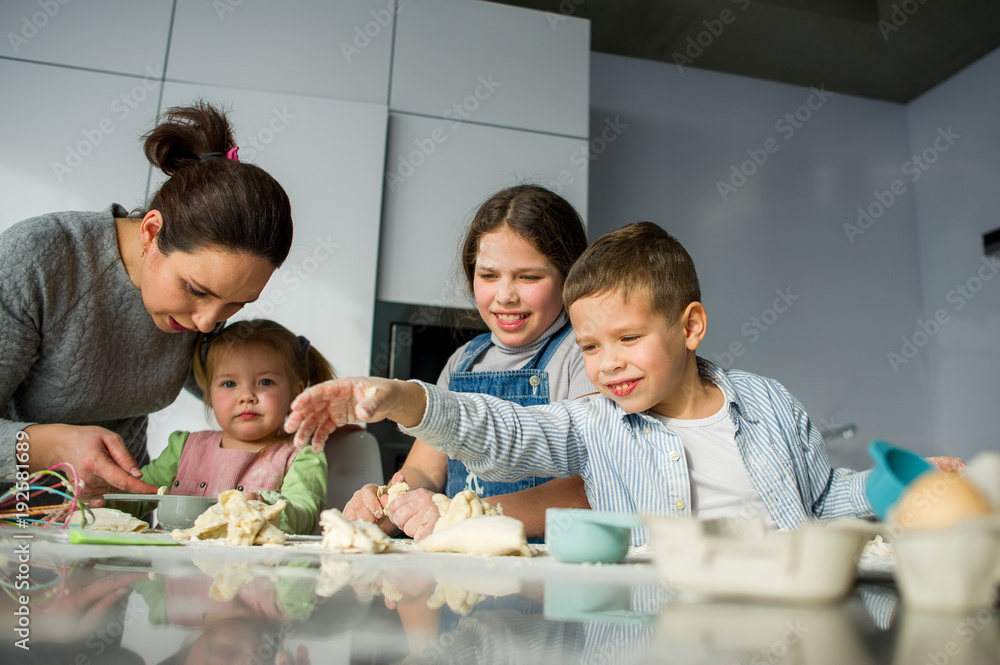 Mother and three children prepare something from the dough. Mother and three children prepare something from the dough.