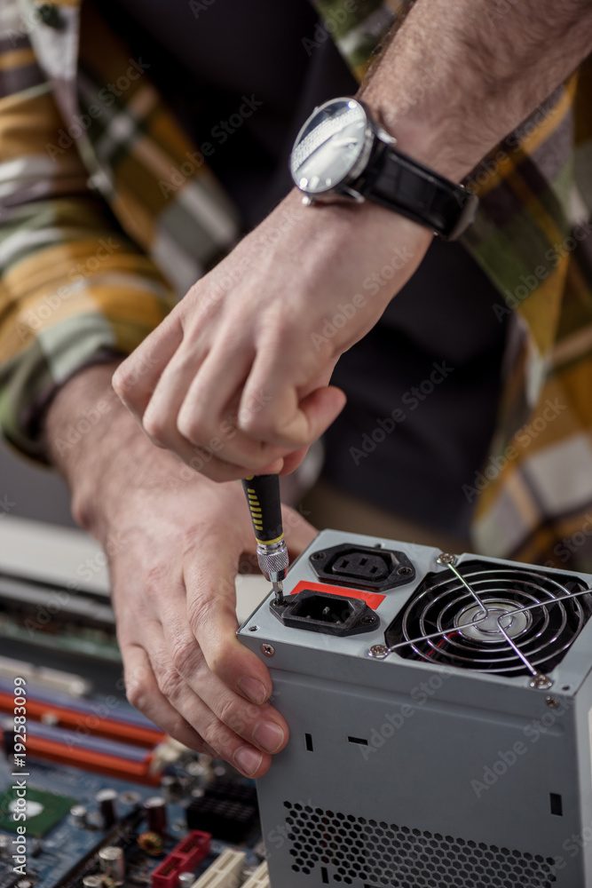 cropped image of repairman fixing computer part with screwdriver cropped image of repairman fixing computer part with screwdriver