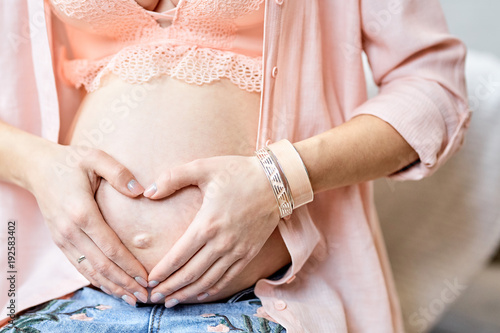 Pregnant woman holding hands in shape of heart on belly