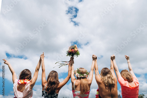 Girls raised their hands up on cloudy sky background at hawaii style hen party