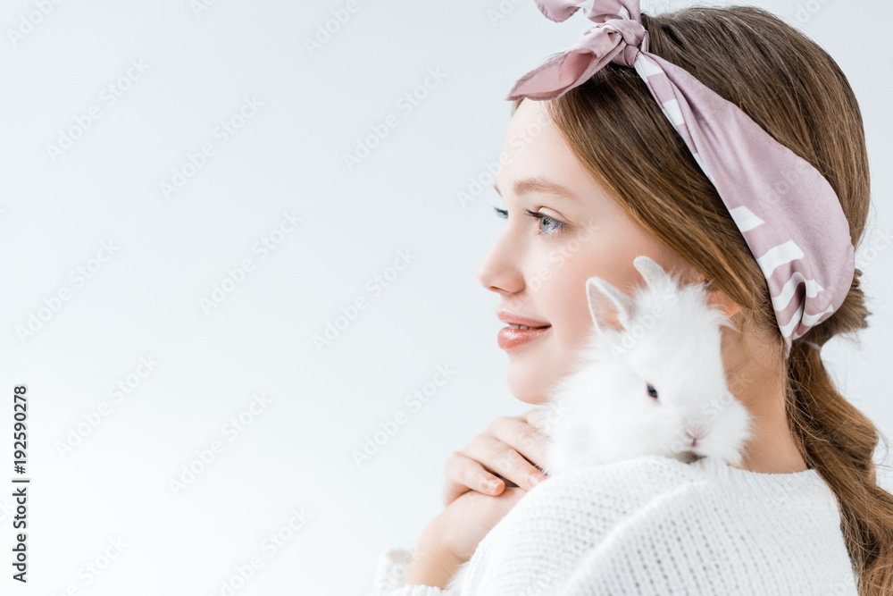 side view of smiling girl holding adorable white rabbit isolated on white side view of smiling girl holding adorable white rabbit isolated on white