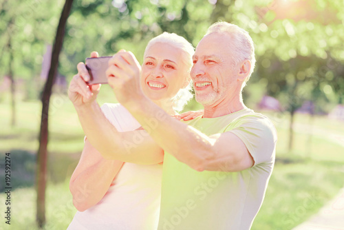 Sweet memory. Portrait of elderly family expressing cheer while using mobile phone and making selfies