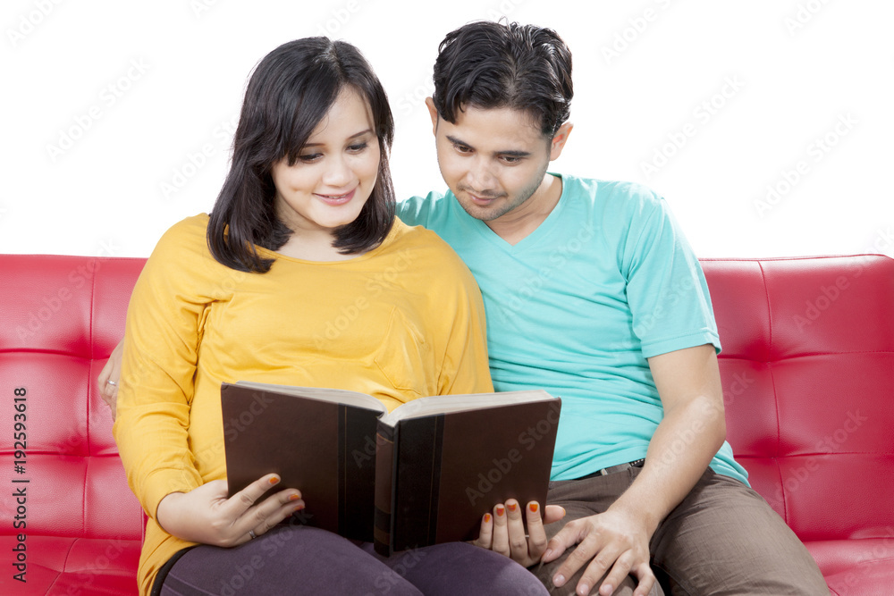 Loving husband reading together with pregnant wife Loving husband reading together with pregnant wife